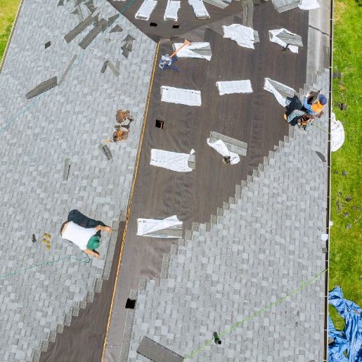 Roofer working on replacement asphalt shingle roof